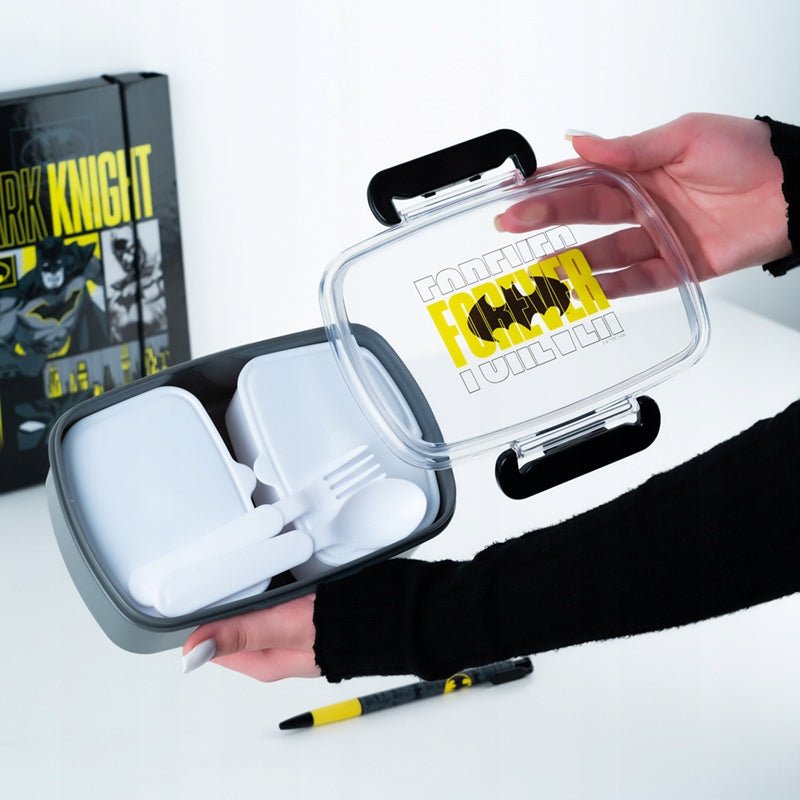 Otwarty lunchbox Batman trzymany w dłoniach, pojemnik na śniadanie ze sztućcami dla dzieci