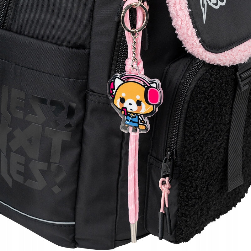 Tematyczna zawieszka z postacią Aggretsuko przy czarnym plecaku.